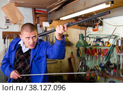 Confident gunsmith lubricates and cleans barrel of rifled shotgun. Стоковое фото, фотограф Яков Филимонов / Фотобанк Лори