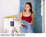 Young woman with palette of colors in hands selects harmonious color of paint with existing tiles. Стоковое фото, фотограф Яков Филимонов / Фотобанк Лори