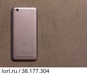 Adygea, Russia - January 3, 2018: Chinese smartphone Xiaomi Redmi 5A silver back side close up view from above on grey background with copy space. Редакционное фото, фотограф Андрей С / Фотобанк Лори