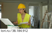 emale foreman in a protective helmet and a yellow vest checks the execution of repair work using a laptop. Стоковое видео, видеограф Яков Филимонов / Фотобанк Лори