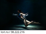 Slender pretty young woman brunette in bathing suit and white blouse in dark pond, illuminated by moonlight. Elegant female underwater. Concept of beauty, tenderness and striving for ideal. Copy space. Стоковое фото, фотограф Aleksandr Golubev / Фотобанк Лори