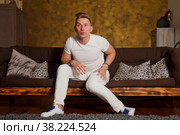 Fashionable man in white clothes doesn't understand something and looks away. An Emotional cute young guy at home in interior room. Emotional portrait concept. Copyright space. Стоковое фото, фотограф Aleksandr Golubev / Фотобанк Лори