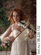 Pretty, slender woman with violin and wings. Female in stage image of an angel. Emotions of girl in dress standing in an old textured interior room. Actress shows her abilities. Author space in photo. Стоковое фото, фотограф Aleksandr Golubev / Фотобанк Лори