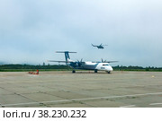 Standing plane and helicopter taking off in the background at the airport of Kunashir island (2022 год). Редакционное фото, фотограф Евгений Харитонов / Фотобанк Лори