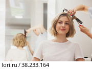 Hairdresser does hairstyle cute pretty young woman in beauty salon. Customer service in interior room create an amazing image. Work hairstyles creation wizard. Concept style, satisfaction. Copy space. Стоковое фото, фотограф Aleksandr Golubev / Фотобанк Лори