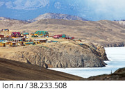 Lake Baikal in early spring. Top view of the village of Sakhyurta and the wooden houses of tourist bases on the coastal rocks. Snowless hills on the shore of Tutai Bay with melting ice. Spring travel (2015 год). Стоковое фото, фотограф Виктория Катьянова / Фотобанк Лори