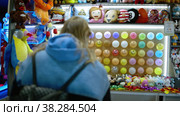 Woman popping a balloon with a dart in amusement park. Стоковое видео, видеограф Данил Руденко / Фотобанк Лори