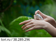 Woman's hand applies cream on nature background, close up. Female hands with cosmetic tube. Selective focus. Стоковое фото, фотограф Юлия Тарасова / Фотобанк Лори