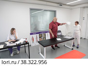 Сергей Михайлович Бубновский тестирует костно-мышечную систему пациентки (2022 год). Редакционное фото, фотограф Дмитрий Неумоин / Фотобанк Лори