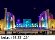 A few tourists on Registan square in Samarkand with Ulugbek madrasah, Sherdor madrasah and Tillya-Kari madrasah at moon night with multicolored backlight. Uzbekistan (2019 год). Стоковое фото, фотограф Наталья Волкова / Фотобанк Лори