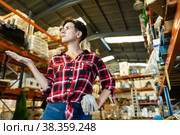 Thoughtful female storekeeper looking for tedious goods in building materials warehouse indoor. Стоковое фото, фотограф Яков Филимонов / Фотобанк Лори