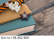 St. George's ribbon and the Order of the Red Star of the USSR World War II veteran on a wooden background. Translation into Russian: Workers of all countries unite. The concept of the May 9 holiday. (2022 год). Стоковое фото, фотограф Photojuli / Фотобанк Лори