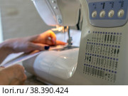Close-up of the seamstress's hands at the sewing machine hem fabric, clothing. Стоковое фото, фотограф Игорь Кляхин / Фотобанк Лори