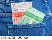 Banknotes of Norwegian krone sticking out of the blue jeans pocket. Стоковое фото, фотограф FotograFF / Фотобанк Лори