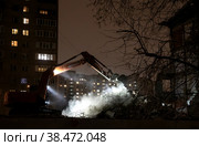 Москва, микрорайон Марфино, улица Академика Комарова, дом 8. Эскаватор работает ночью на развалинах сносимого в рамках программы реновации дома. Рядом светятся окна многоэтажного многоквартирного жилого дома (2022 год). Редакционное фото, фотограф Наталья Николаева / Фотобанк Лори