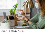 Коронавирус и грипп. Деловая женщина, работающая в офисе в защитной маске. Деловая женщина на карантине из-за коронавируса в защитной маске. Работа из дома. Моет руки дезинфицирующим гелем. Стоковое фото, фотограф Photojuli / Фотобанк Лори