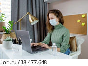 Женщина в медицинской маске занимается офисной работой удаленно из дома. Использование компьютера. Дистанционное обучение, карантин, онлайн-образование и работа. Стоковое фото, фотограф Photojuli / Фотобанк Лори