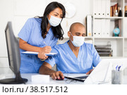 Two physicians in medical masks working with case histories on laptop. Стоковое фото, фотограф Яков Филимонов / Фотобанк Лори
