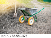 wheelbarrow with a shovel and gravel. as part of a construction project, a man is transporting rubble on a hand wheelbarrow. Paving the road with gravel. Construction with your own hands. Стоковое фото, фотограф Оксана Медведева / Фотобанк Лори