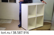 A man installs plugs on euro screws. Demonstrates assembled modular shelving. Assembling a modular rack. Overall plan. Стоковое видео, видеограф Vadzim Yakubovich / Фотобанк Лори