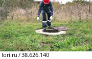 A male plumber in overalls descends into an open water well. Inspection of water meter readings. Стоковое видео, видеограф Коханова Наталья / Фотобанк Лори