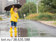 A small child in rainbow socks, yellow rubber boots and a jacket runs through puddles, has fun and plays after the rain. A picture of summer and autumn holidays. A child under an umbrella. (2022 год). Стоковое фото, фотограф Photojuli / Фотобанк Лори