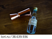 Ром и барный джиггер на деревянном столе. Стоковое фото, фотограф Наталья Гилинская / Фотобанк Лори