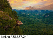 Dragon Crest mountain Krabi Thailand, a Young traveler sits on a rock that overhangs abyss at sunset. Стоковое фото, фотограф Fokke Baarssen / Фотобанк Лори