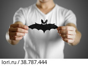 A man in a white t-shirt holds a black silhouette of a bat. Close up. Стоковое фото, фотограф Плотников Дмитрий / Фотобанк Лори