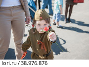 Портрет ребенка в военной форме с цветами 9 мая. Улыбающаяся девочка 5 лет поздравляет ветеранов цветами. Празднование Дня Победы. 9 мая 2015 года, Коломна, Московская область, Россия. Редакционное фото, фотограф Оксана Медведева / Фотобанк Лори