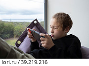 Boy teenager being attracted with game on handheld console. Стоковое фото, фотограф Данил Руденко / Фотобанк Лори