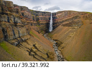 Aerial view of Hengifoss waterfall in East Iceland. Hengifoss is the third highest waterfall in Iceland and is surrounded by basaltic strata with red layers of clay between the basaltic layers (2020 год). Стоковое фото, фотограф Igor Tichonow / Фотобанк Лори