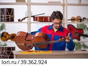 Young man repairing musical instruments at workshop. Стоковое фото, фотограф Elnur / Фотобанк Лори