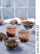 Decoction of pine nut shells in glasses, pine nuts and cones on the table. Alternative medicine. Vertical view. Стоковое фото, фотограф Елена Руй / Фотобанк Лори
