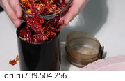 A man pours dried red peppers into a coffee grinder. Grinding hot pepper. Close-up. Стоковое видео, видеограф Vadzim Yakubovich / Фотобанк Лори