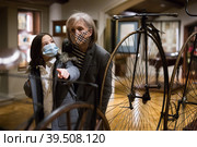 Elderly woman with preteen granddaughter in protective masks examining retro bicycles in museum. Стоковое фото, фотограф Яков Филимонов / Фотобанк Лори