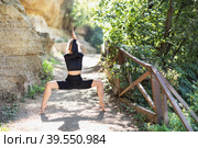 Young woman in black sportswear practicing yoga doing Utkata Konasana exercise, goddess pose, exercising in the park on a warm summer morning. Стоковое фото, фотограф Сергей Чайко / Фотобанк Лори