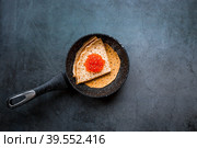 Русские традиции. Широкая масленица. Блины на сковороде и красная икра на темном фоне. Крупный план. Стоковое фото, фотограф Photojuli / Фотобанк Лори