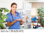 Portrait of a young woman doctor in a office, holding an outpatient patient card in her hands. Стоковое фото, фотограф Яков Филимонов / Фотобанк Лори
