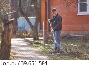 The gardener is raking autumn leaves in the garden on the background of a red brick cottage. Стоковое фото, фотограф Кутина Татьяна / Фотобанк Лори