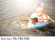 Girl in a hat swimming in the river with inflatable circle in the shape of a lama. Inflatable alpaca for a child. Sea with a sandy bottom. Beach holidays, swimming, tanning, sunscreens. Стоковое фото, фотограф Ольга Симонова / Фотобанк Лори