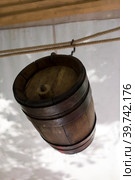 Old wine barrel with iron rings is suspended from a metal hook. Стоковое фото, фотограф Iva Noel / Фотобанк Лори