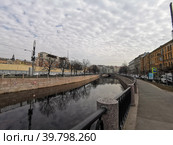 Набережная реки Карповки, в воде отражаются деревья и небо с облаками, вдали виден Силин мост (2021 год). Редакционное фото, фотограф Елена Яворская / Фотобанк Лори