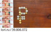 The symbol of Russian currency Ruble is made of ruble coins and a row of paper banknotes of 5000 rubles on wooden background. Money  and finance concept. Top view, copy space, flat lay, mock up. Стоковое фото, фотограф Виктория Катьянова / Фотобанк Лори