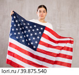 Contented young woman holding USA flag against unicoloured background. Стоковое фото, фотограф Яков Филимонов / Фотобанк Лори