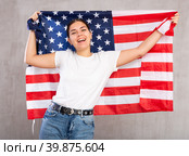Joyous young woman holding USA flag against unicoloured background. Стоковое фото, фотограф Яков Филимонов / Фотобанк Лори