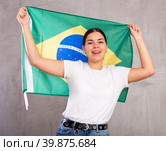 Joyous young woman holding Brazil flag against unicoloured background. Стоковое фото, фотограф Яков Филимонов / Фотобанк Лори