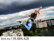 Мужчина прыгает с веревкой на фоне грозовых туч, роупджампинг (2015 год). Редакционное фото, фотограф Сергей Васильев / Фотобанк Лори