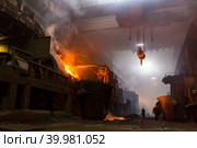 Производство меди на металлургическом заводе. Рабочий из шланга льёт известковый раствор на конвертер с расплавленным металлом. Яркое пламя, дым. Медный завод, Норильск, Красноярский край, Россия. Стоковое фото, фотограф Андрей Степанов / Фотобанк Лори