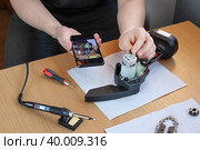 Неопытный человек смотрит в смартфон чтобы правильно отремонтировать прибор. Стоковое фото, фотограф Vladimir Vikhrov / Фотобанк Лори